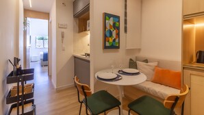 Un espace de vie compact comprenant un coin repas, une kitchenette et un canapé avec un coussin.