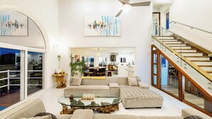 A spacious living room with a large sectional sofa, a glass coffee table, and a staircase. - 360 views Ocean and Jungle villa in amazing Ocotal! Enjoy the paradise! (Guanacaste province)