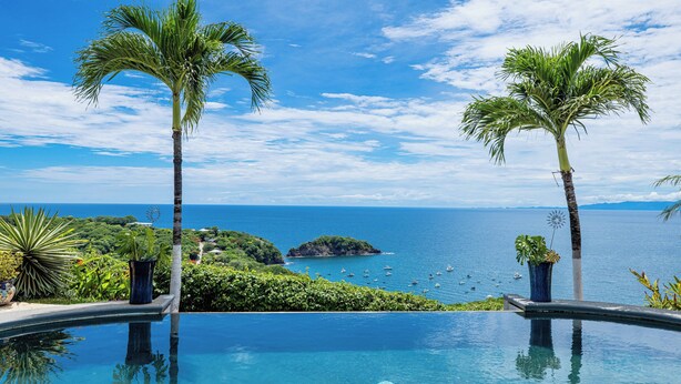 A pool with a view of the ocean and palm trees. - 360 views Ocean and Jungle villa in amazing Ocotal! Enjoy the paradise! (Guanacaste province)