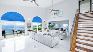 A spacious living area with a large window overlooking the sea, a modern staircase, and a dining area with a view. - 360 views Ocean and Jungle villa in amazing Ocotal! Enjoy the paradise! (Guanacaste province)