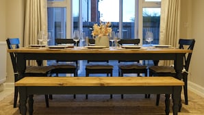 Une table à manger dressée avec des verres à vin, des assiettes et un vase rempli de fleurs séchées.