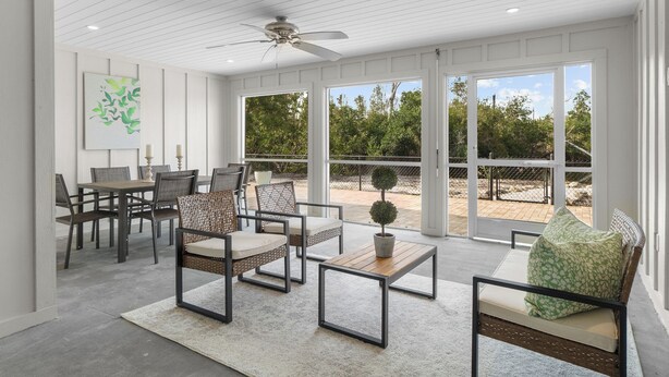 Une vaste terrasse dotée d’un espace repas, comprenant une table et des chaises, ainsi qu’un ventilateur de plafond.