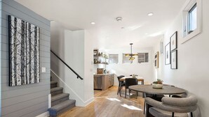 A spacious kitchen with modern appliances, a dining area with a round table and chairs, and a staircase leading to another level.