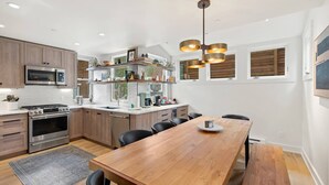 A modern kitchen with wooden cabinets, stainless steel appliances, and a wooden dining table.