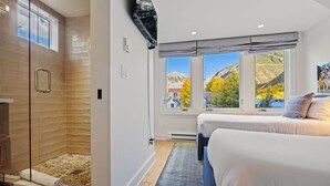 A bedroom with a large window, a shower, and a bed.