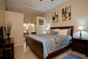 A bedroom with a large bed, bedside tables, a TV, and artwork on the walls.