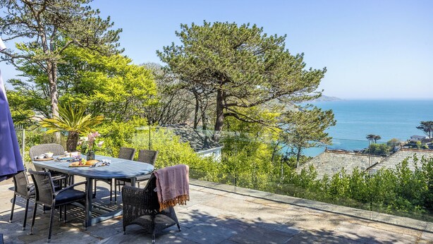 An outdoor dining area with a table and chairs, overlooking a coastal view with trees and a clear sky. - Moult Sylvan, Homely 4 bed, stunning sea views, Salcombe (Salcombe)