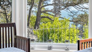 A room with a large window, a wooden chair, a sofa, and two glass jars on the windowsill. - Moult Sylvan, Homely 4 bed, stunning sea views, Salcombe (Salcombe)