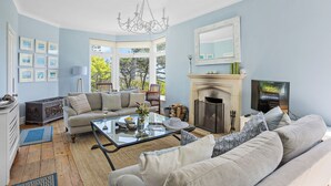 A living room with a fireplace, a sofa, a coffee table, and a chandelier. - Moult Sylvan, Homely 4 bed, stunning sea views, Salcombe (Salcombe)