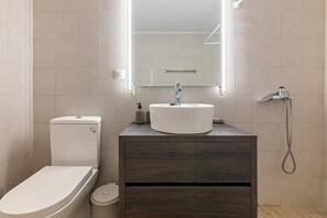A modern bathroom with a toilet, sink, and shower.