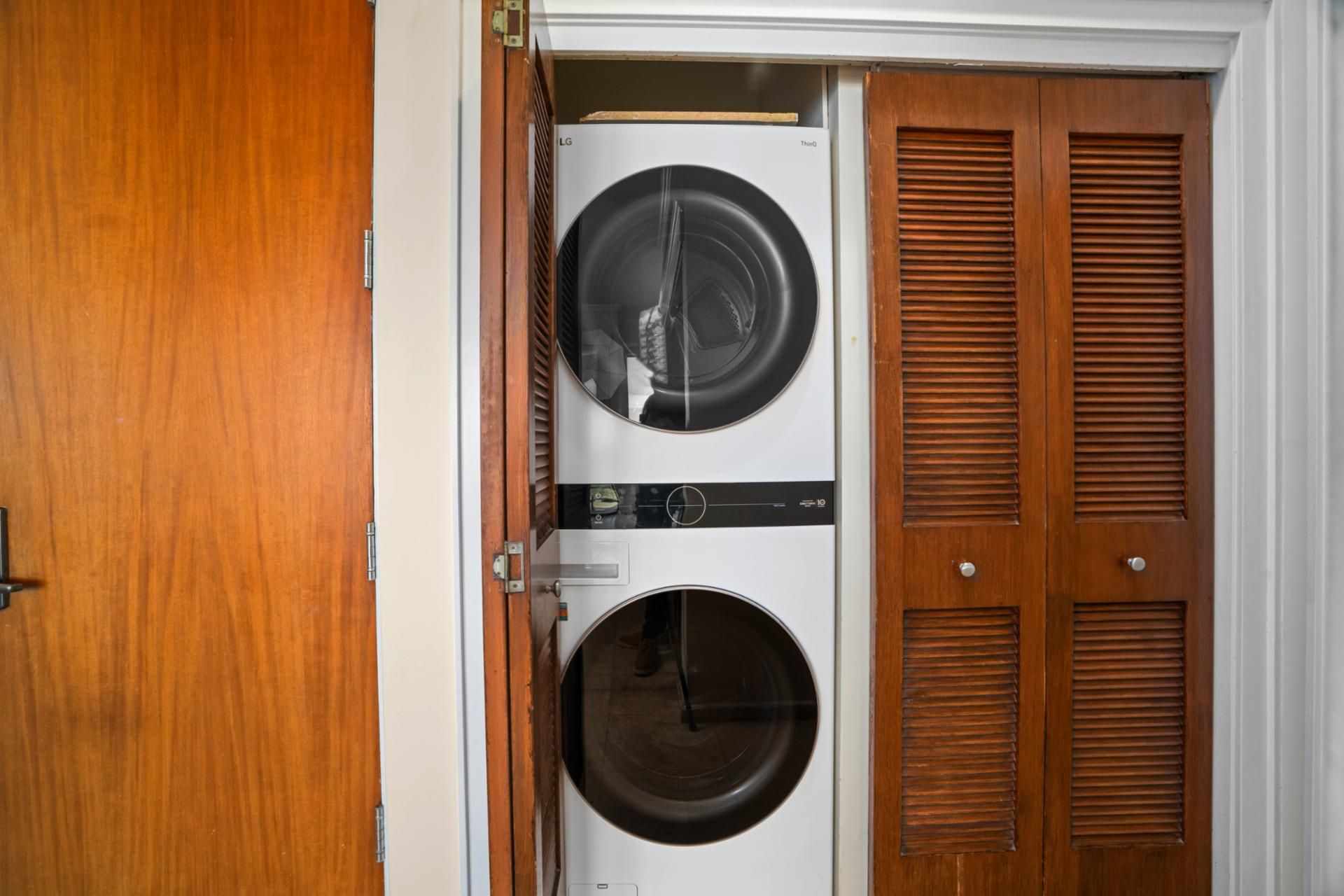 A laundry room with two stacked washers and dryers, wooden doors, and a metal handle.