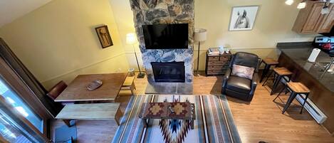A cozy living room with a stone fireplace, a leather sofa, a dining table, and a bar area.