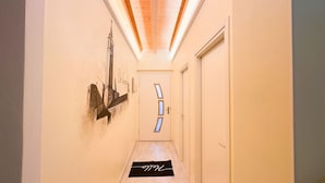 Un couloir doté d’un plafond en bois, d’une porte au design original et d’un tapis noir orné de motifs blancs.
