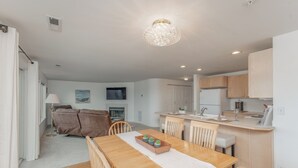 A modern kitchen with wooden cabinets, a central island, and a dining area with a wooden table and chairs. - Park Pointe B102 – Walk to the Beach & Enjoy the Pool & Hot Tub! (Chelan)