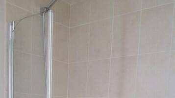 A shower with a chrome handle and a glass door, set in a tiled bathroom.