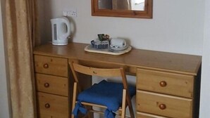 A wooden desk with a chair, a white kettle, and a tray with cups and a small container. - A35 PitStop (Axminster)