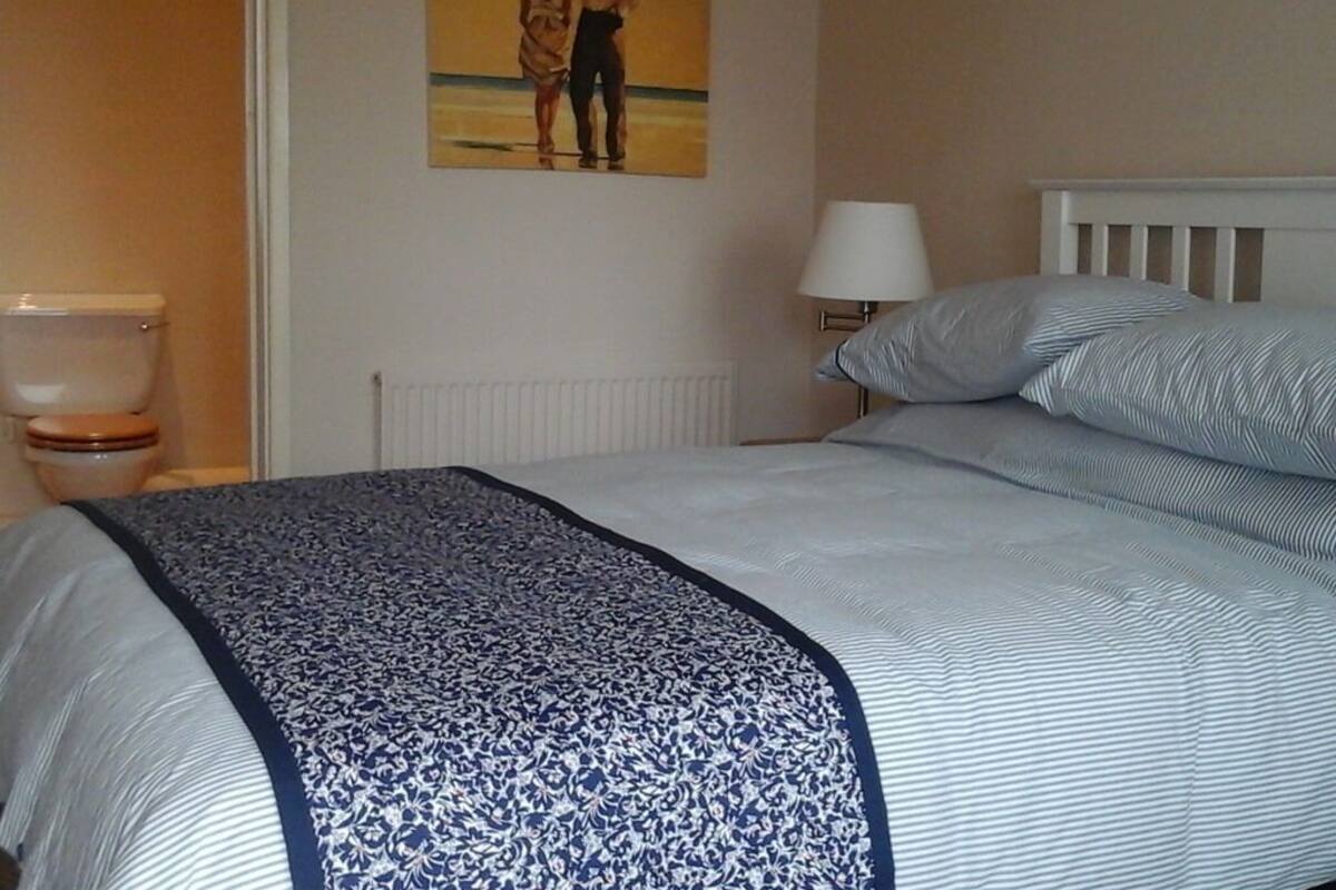 A bedroom with a bed, a nightstand, a lamp, and a poster on the wall.