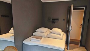 Habitació d'hotel amb dos llits, parets grises i un terra de fusta.