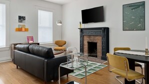 Ein modernes Wohnzimmer mit einem schwarzen Ledersofa, einem Glastisch, einem gelben Sessel und einem Kamin.