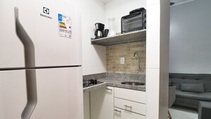 A compact kitchen with a refrigerator, a coffee maker, a toaster, and a sink. - Santa Clara Studio (Rio de Janeiro)