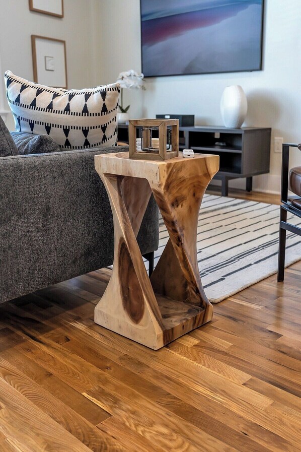 A modern living room with a wooden coffee table, a grey sofa, and a TV in the background. - 4th floor walk-up apartment with perfect mix of historic features with luxurious modern amenities! (Cincinnati)