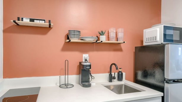 A kitchen with a white countertop, a sink, a coffee maker, a microwave, and a refrigerator. - Room 204 - Two Queens - Kitchenette - NonSmoking (Lincoln)