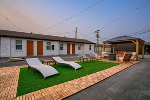 Un bâtiment doté d’un espace extérieur couvert avec des sièges, d’une pelouse et d’un chemin pavé.
