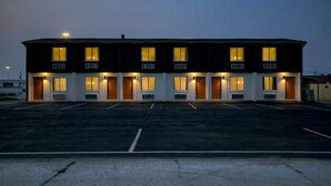 Un motel à deux étages, avec une rangée de chambres, chacune dotée d’une porte et d’une fenêtre.