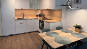 Een moderne keuken met witte kasten, een houten aanrechtblad en een eethoek met een tafel en stoelen.