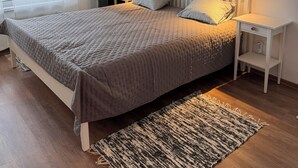 Een slaapkamer met een bed, twee nachtkastjes, een raam met gordijnen en wanddecoratie.