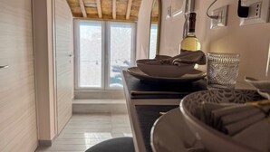 Une cuisine moderne avec un coin repas, caractérisée par un plafond en bois, une grande fenêtre et une bouteille de vin posée sur le comptoir.