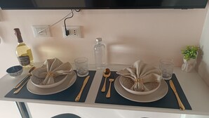 Une table à manger élégamment dressée, avec des assiettes, des couverts et des verres, une bouteille et une petite plante.