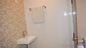 Een badkamer met een wastafel, een handdoek aan een rek en een douchehoek.