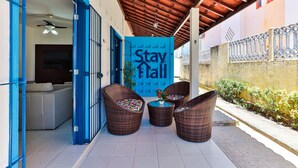 A covered outdoor seating area with wicker furniture and a 'Stay Hall' sign. - Casa 11 Villa Giardino-SH033 (Tamandaré)
