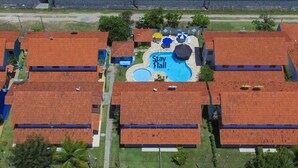 A hotel with red-tiled roofs, a central pool area labeled "Stay Flail," and multiple guest rooms arranged around the pool. - Casa 11 Villa Giardino-SH033 (Tamandaré)