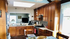 A kitchen with wooden cabinets, a stove, a sink, and a dining table with placemats.