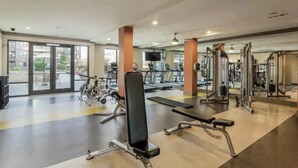 Ein geräumiger Fitnessraum mit Cardiogeräten, Kurzhanteln und einem Bereich für Langhantelübungen.