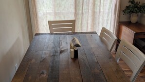 Una mesa de comedor con cubierta de madera rústica, rodeada de sillas blancas con asientos acolchados.