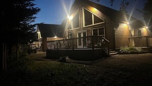 A wooden house with a deck and multiple windows, surrounded by trees. - Indian Falls Chalets  (Springdale)