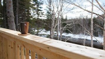 A wooden deck with a metal cup on a coaster.