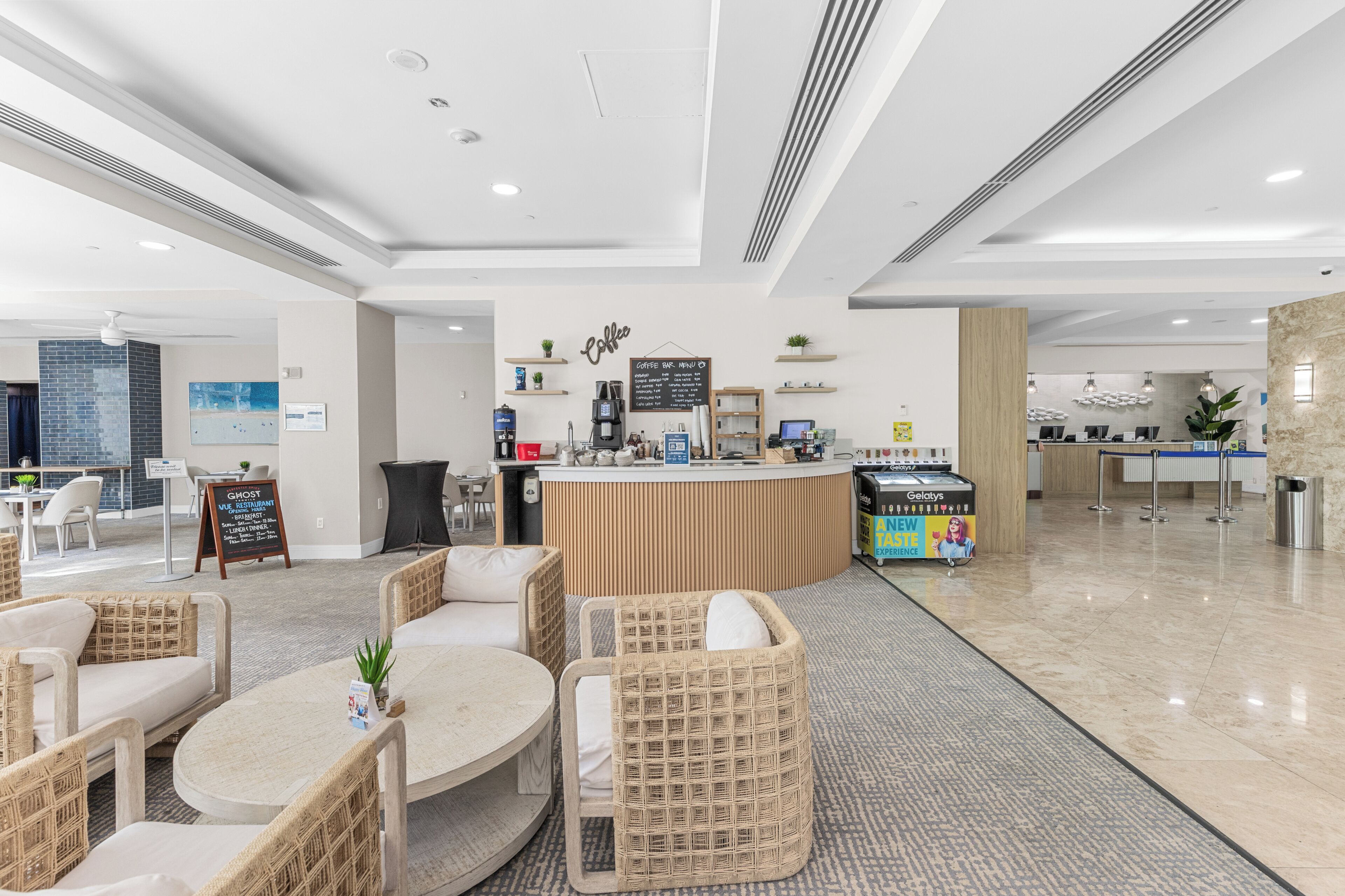 A modern hotel lobby with a coffee bar, seating area, and a reception desk.