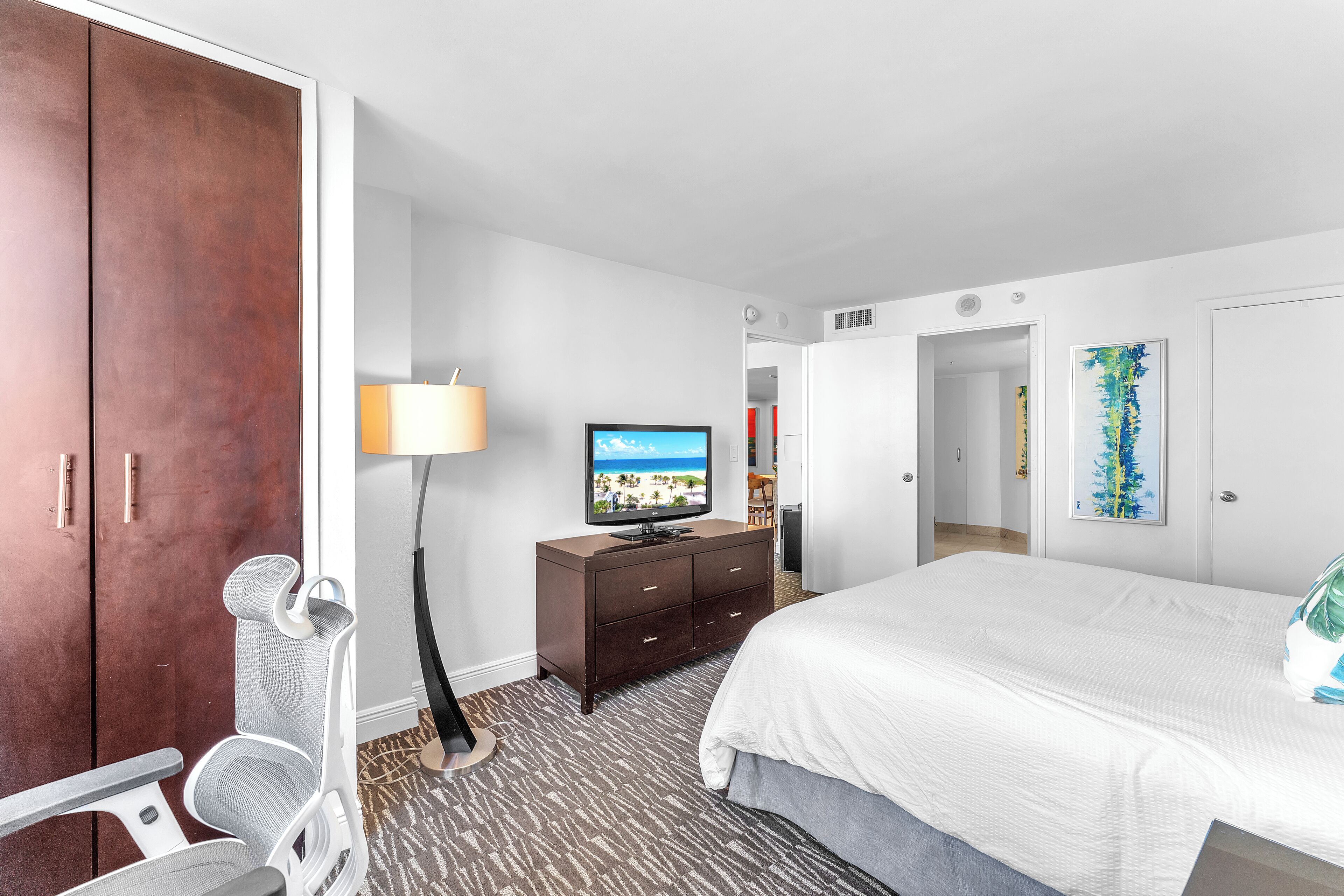 A hotel room with a bed, a television, a desk, and a wardrobe.
