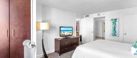 A hotel room with a bed, a television, a desk, and a wardrobe.