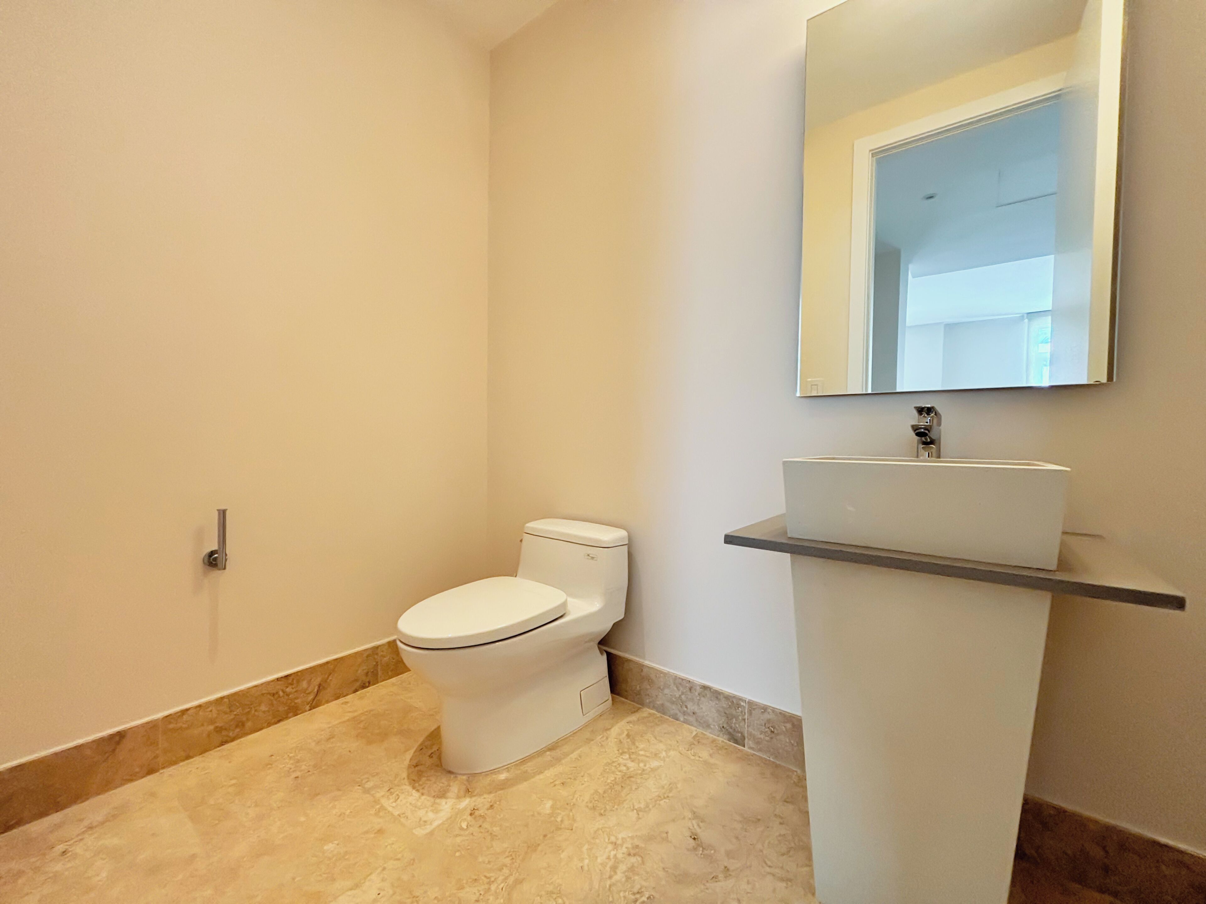 A bathroom with a toilet, a sink, and a mirror.