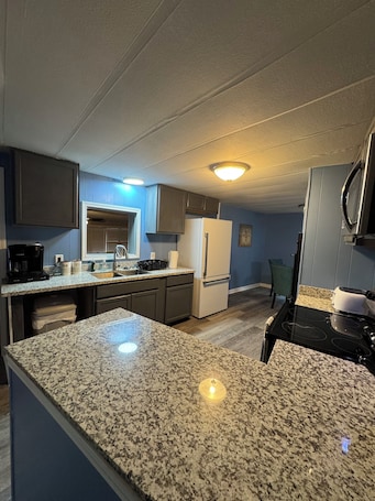 A kitchen with granite countertops, a refrigerator, a stove, and a microwave.