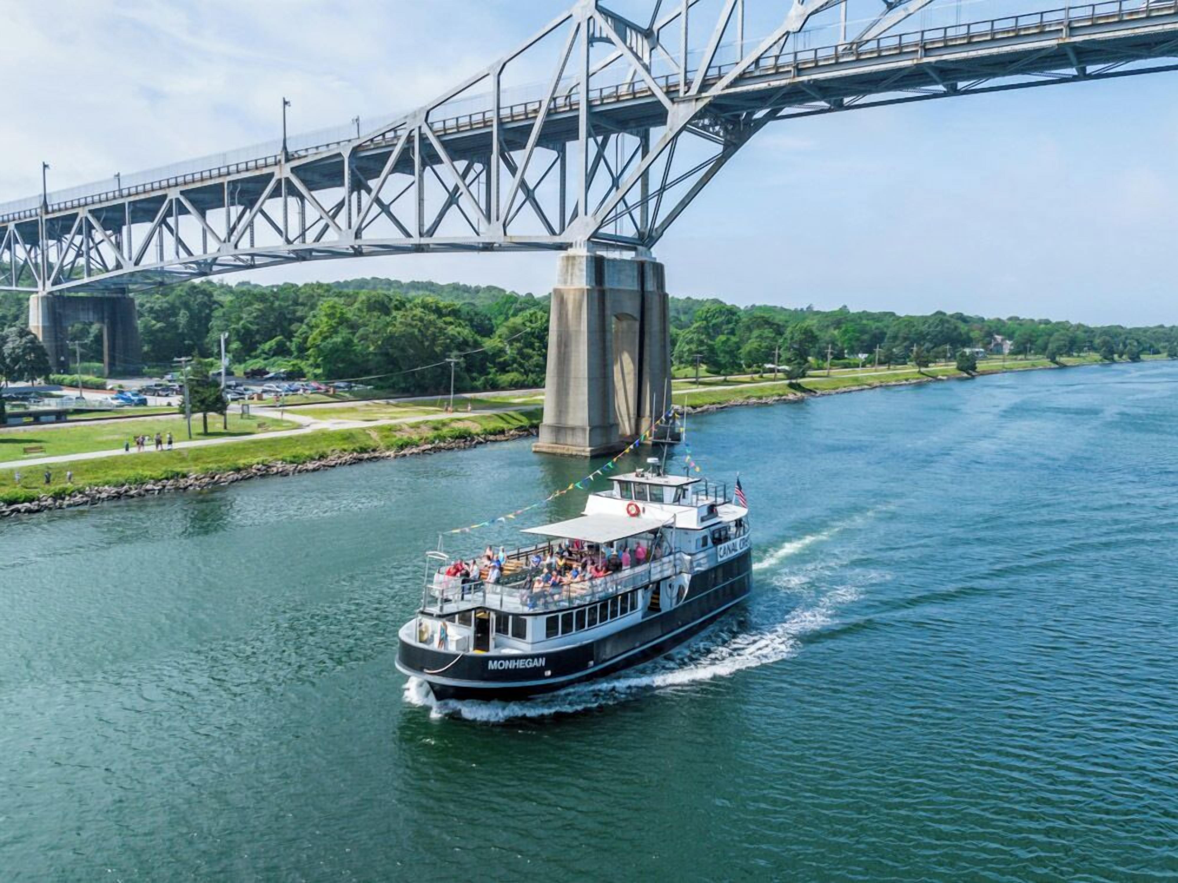 A riverboat named 'Monhegan' traveling under a large bridge.