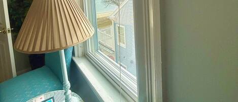A corner room with a window, a lamp, a small table with a brochure, and a blue chair.
