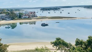 Una vista costiera con un mare tranquillo, imbarcazioni e una spiaggia sabbiosa.