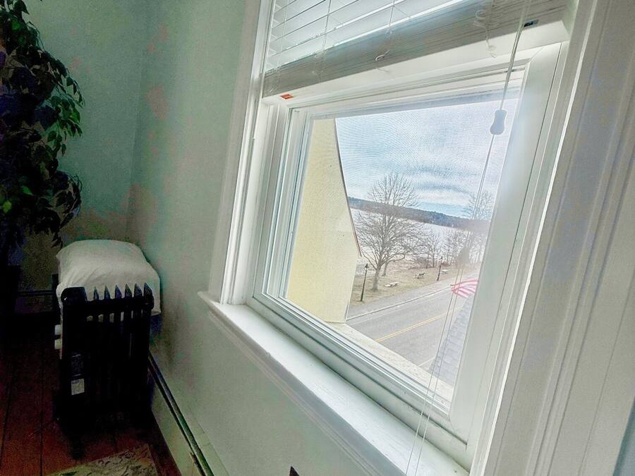 Quarto com uma janela grande, um radiador e uma planta.