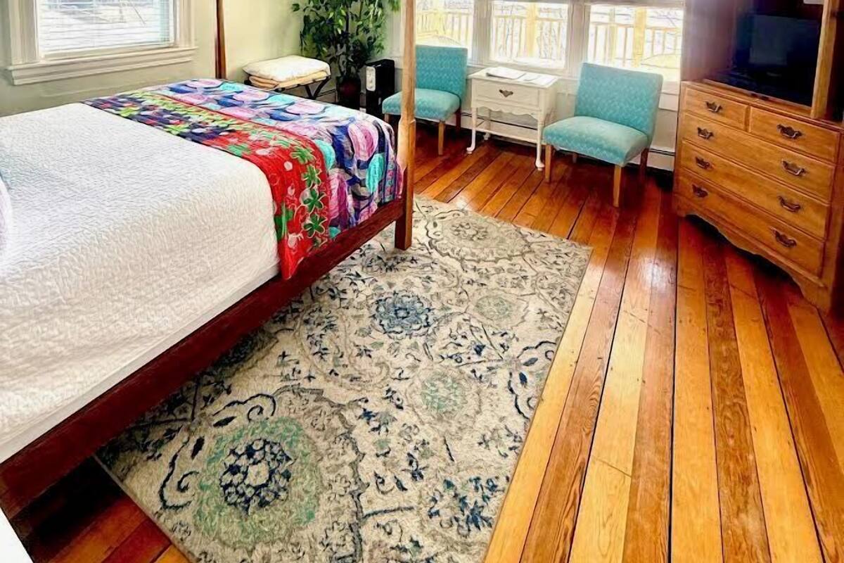 Ein Schlafzimmer mit einem Bett, einem Schreibtisch, einem Stuhl, einem Kleiderschrank, einem Deckenventilator und einem Fenster.
